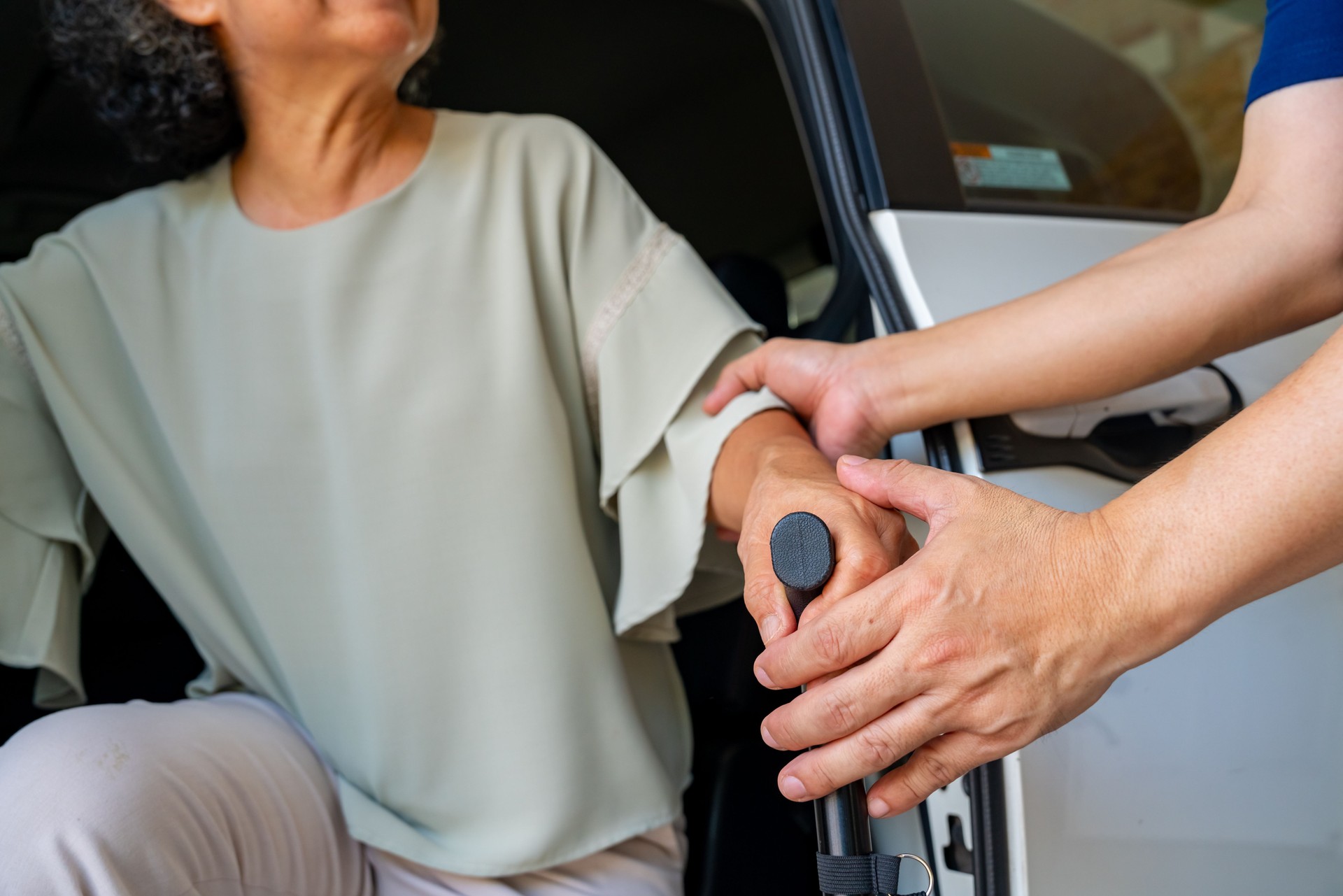Caregiver helping senior woman get in the car.